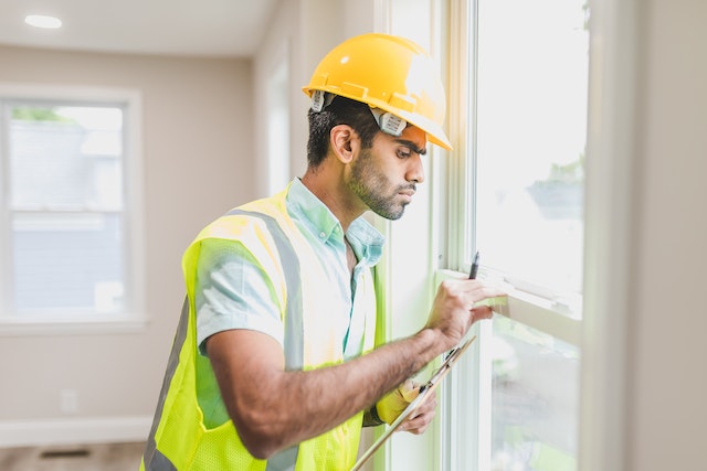 a person in a vest and hardhat inspecting a window